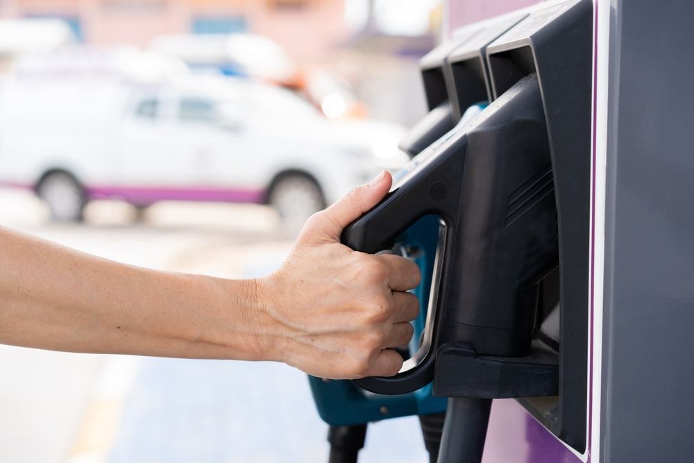 Hand holding an EV charging connector at a charger